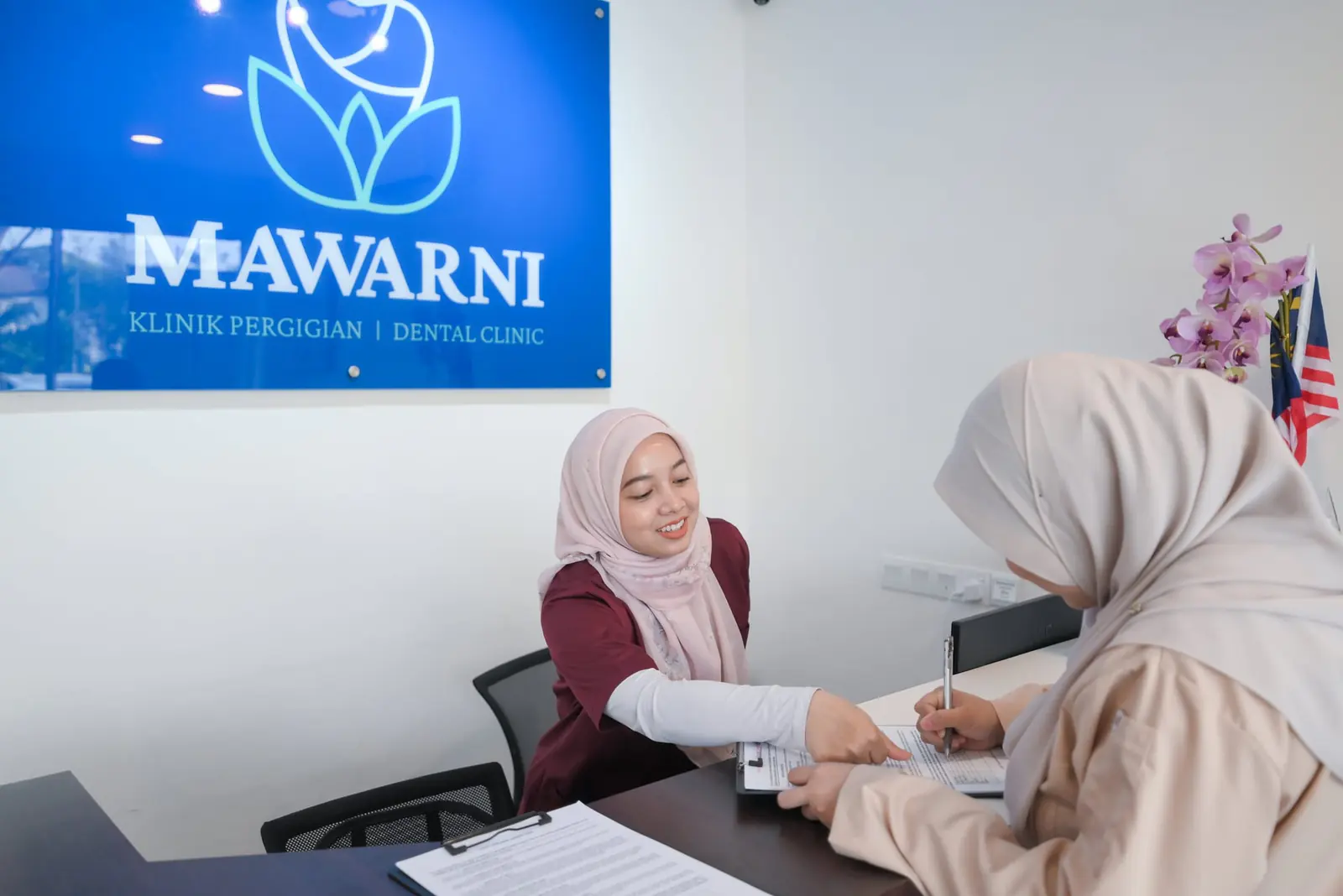 A patient registering at the Mawarni Dental Clinic front counter